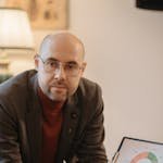 A professional man in an office setting presenting a circle graph on a clipboard.